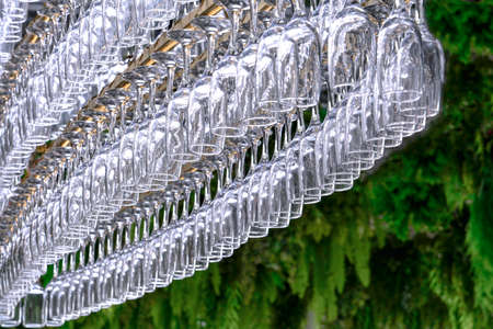 A large number of glasses in the form of an oval hang on the holder at the bar.の写真素材