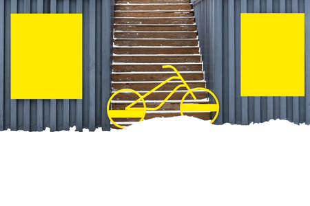 On the walls of garages hang yellow shields, between which stands a bicycle and blocks the entrance to the stairs.の写真素材