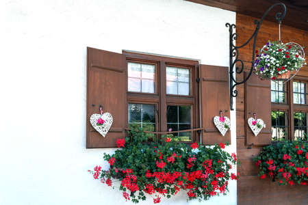 The windows of the wooden house are beautifully decorated with white hearts and flowersの写真素材