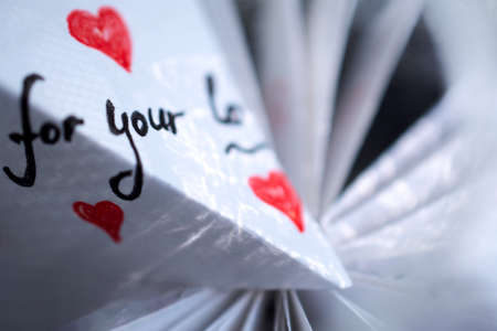 A white note with hearts and words of gratitude lies on a pile of papersの写真素材