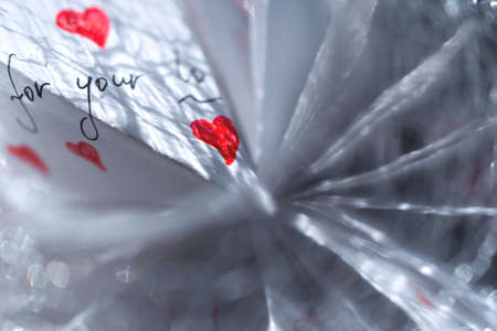 A white note with hearts and words of gratitude lies on a pile of papersの写真素材