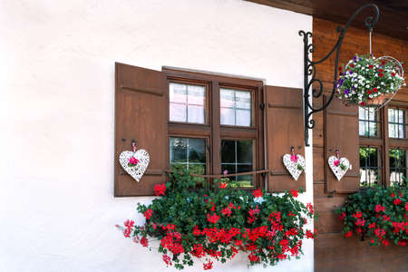 The windows of the wooden house are beautifully decorated with white hearts and flowersの写真素材