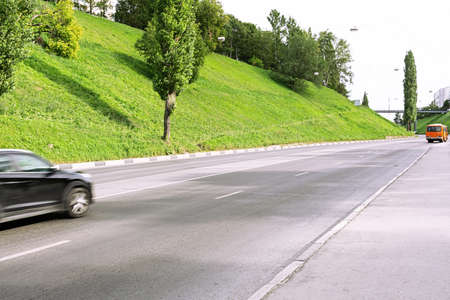 A bright orange bus is moving along an empty road.の写真素材