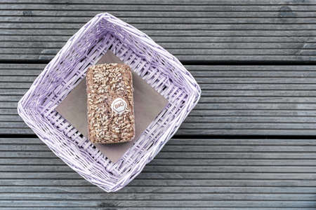 A loaf of bread lies in a lilac basket on a wooden tableの写真素材