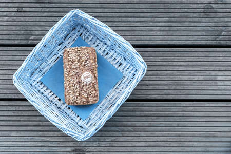 A loaf of bread lies in a blue basket on a wooden tableの写真素材