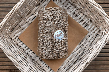 A loaf of bread lies in a beige basket on a wooden tableの写真素材