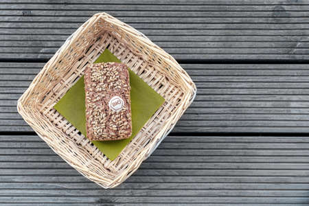 A loaf of bread lies on a green napkin in a beige basket on a wooden tableの写真素材