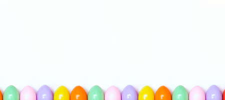 Top view of an Easter composition of painted eggs in bright juicy colors on a white background. Banner. Holiday concept, flat layout, minimalism.の写真素材
