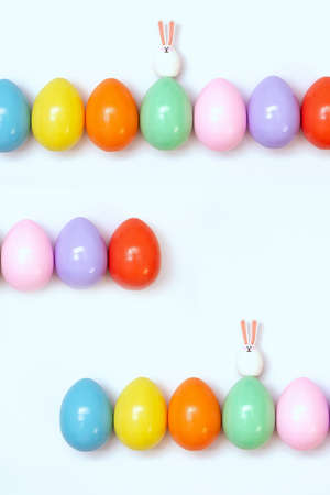 Top view of an Easter composition of painted eggs in bright juicy colors on a white background with...