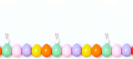 Top view of an Easter composition of painted eggs in bright juicy colors on a white background with two little rabbits. Holiday concept, flat layout, minimalism.の写真素材
