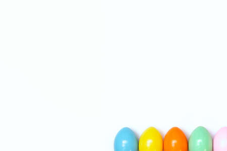 Top view of an Easter composition of painted eggs in bright juicy colors on a white background with a glossy texture. Holiday concept, flat layout, minimalismの写真素材