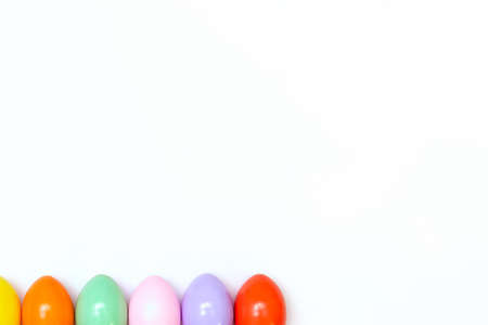 Top view of an Easter composition of painted eggs in bright juicy colors on a white background with a glossy texture. Holiday concept, flat layout, minimalismの写真素材
