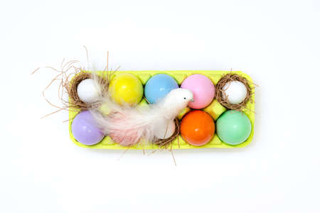 Top view of an Easter composition of painted eggs in bright juicy colors with a glossy texture that lie in the container and a white bird sits on top. Holiday concept, flat layout, easter, backgroundの写真素材