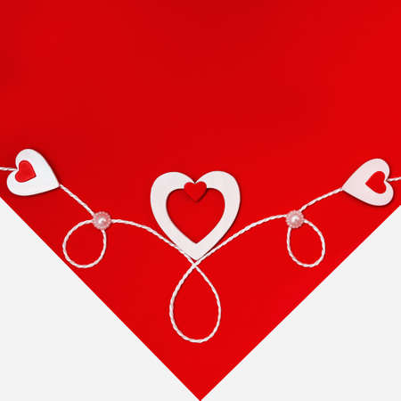 Top view of the composition for Valentines Day with a white envelope from which you can see a red card with white hearts and a ribbon. Holiday concept, greeting card, background.の写真素材