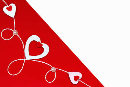 Top view of a composition for Valentines Day on a red and white background with white and red hearts and a white rope. Holiday concept, greeting card, background.の写真素材