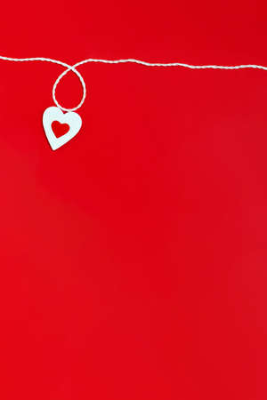Top view of a minimalistic composition for Valentine's day on a red background with white and red hearts and a white rope. Holiday concept, greeting card, background, minimalismの写真素材