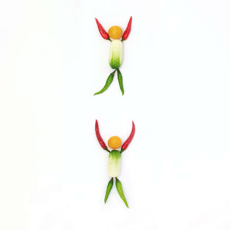 Top view of a flat lay over abstract background of a joyful man and woman who are laid out from vegetables on a white background with copy space. The concept of equality, design, healthy eating.の写真素材