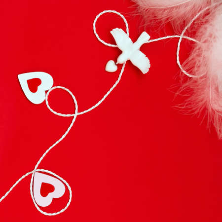Top view of a composition for Valentine's Day on a red background with white and red hearts, feathers pigeon and white rope. Holiday concept, greeting card, backgroundの写真素材