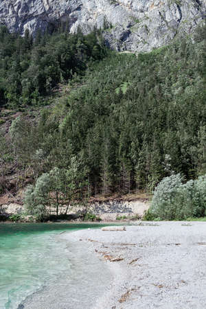 View of a wild beach with white pebble mountain lake with turquoise color of water, cliffs and forest. The concept of nature, mountains, track, travelの写真素材