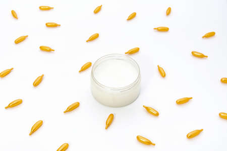 Top view on a jar of white cream and gold capsules with collagen on a white background. The concept of beauty, facial skin care, cosmetology, medicineの写真素材