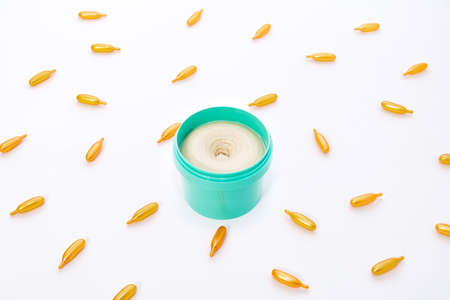 Top view on a bright turquoise jar of cream and golden capsules with collagen on a whiteの写真素材