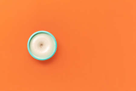 Top view on a bright jar of turquoise color with cosmetic cream on an orange background. The concept of beauty, medicine, facial and body skin care, hair careの写真素材