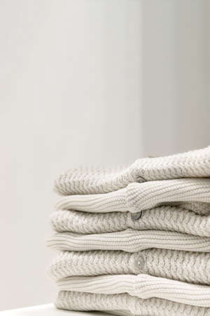 Beige sweaters made from natural fabrics are folded on the tableの写真素材