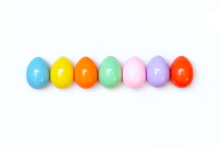 Top view of an Easter composition of painted eggs in bright juicy colors on a white background with a glossy texture. Holiday concept, flat layout, minimalismの写真素材