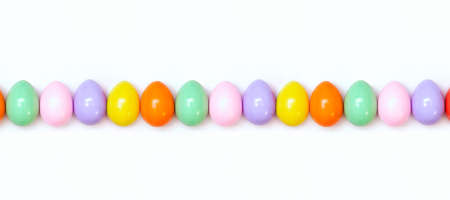 Top view of an Easter composition of painted eggs in bright juicy colors on a white background. Banner. Holiday concept, flat layout, minimalismの写真素材