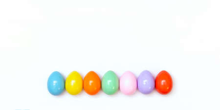 Top view of an Easter composition of painted eggs in bright juicy colors on a white background with a glossy texture. Holiday concept, flat layout, minimalismの写真素材