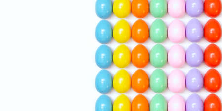 Top view of an Easter composition of painted eggs in bright juicy colors on a white background with a glossy texture that lie in even rows. Holiday concept, flat layout, background, advertisement.の写真素材
