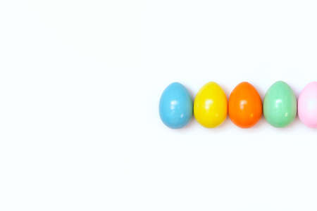Top view of an Easter composition of painted eggs in bright juicy colors on a white background with a glossy texture. Holiday concept, flat layout, minimalismの写真素材