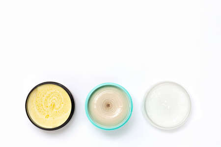 Top view of a black turquoise and white jars with different cream on a white background. The concept of beauty, medicine, facial and body skin care, hair careの写真素材