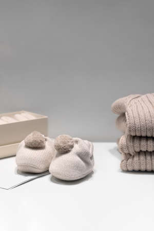 Baby booties, sweaters and socks made of natural beige fabrics lie on the tableの写真素材