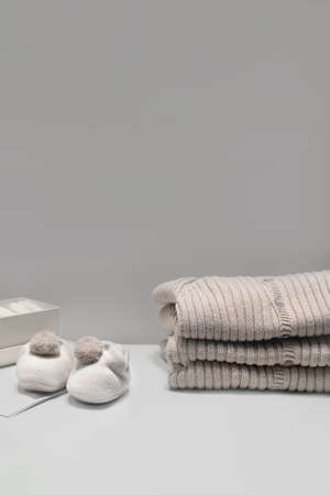 Baby booties, sweaters and socks made of natural beige fabrics lie on the tableの写真素材