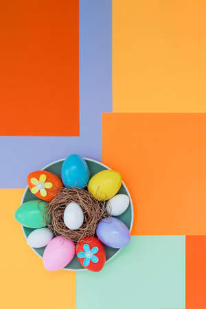Bright background with an asymmetric geometric pattern in a fashionable color scheme with a composition of their Easter eggs and flowers lying on a plate. Concept background, holiday, easterの写真素材