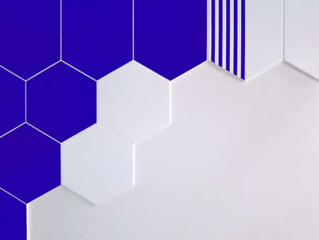 A background of bright blue and white ceramic tiles in the shape of a hexagon that partially covers a white wall. Concept texture, backgroundの写真素材