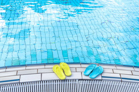 View of yellow and blue flip flops that are standing on a boat by the pool. The concept of summer, vacation, spa, water park, travelの写真素材