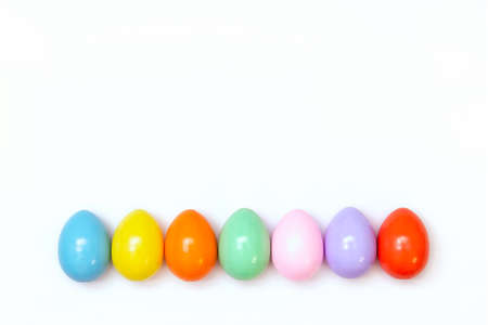 Top view of an Easter composition of painted eggs in bright juicy colors on a white background with a glossy texture. Holiday concept, flat layout, minimalismの写真素材