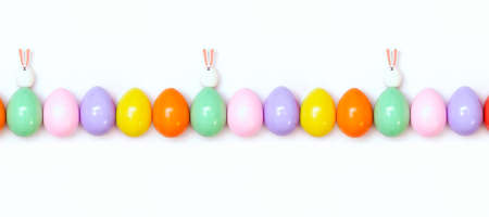 Top view of an Easter composition of painted eggs in bright juicy colors on a white background with two little rabbits. Holiday concept, flat layout, minimalismの写真素材