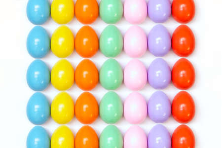 Top view of an Easter composition of painted eggs in bright juicy colors on a white background with a glossy texture that lie in even rows. Holiday concept, flat layout, background, advertisementの写真素材