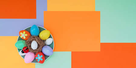 Bright background with an asymmetric geometric pattern in trendy colors with a composition of their Easter eggs, a ladybug and flowers lying on a plate. Concept background, holiday, easterの写真素材