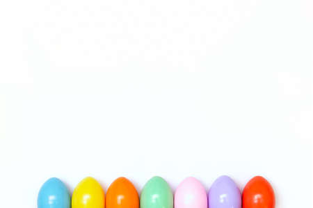 Top view of an Easter composition of painted eggs in bright juicy colors on a white background with a glossy texture. Holiday concept, flat layout, minimalismの写真素材
