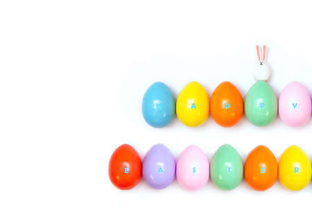Top view of an Easter composition of painted eggs in bright juicy colors on a white background with a glossy texture of a little bunny and the inscription Happy Easter. Holiday concept, minimalismの写真素材