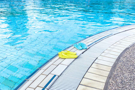 View of yellow and blue flip flops that are standing on a boat by the pool. The concept of summer,...