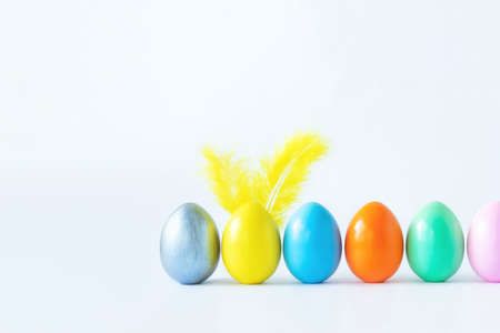 Top view of an easter composition of painted eggs in bright juicy colors on a white background with feather rabbit ears. Vacation concept, flat design, minimalismの写真素材