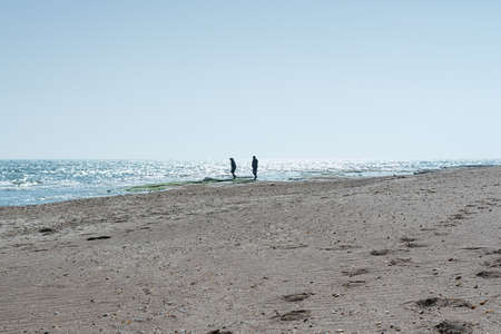 A young couple man and woman walk alone on a deserted beach near the sea. Concept people, landscape, lifestyleの写真素材