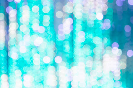 Bright background from blurry bokeh of Christmas lights in turquoise and white. Holiday concept, background, christmasの写真素材
