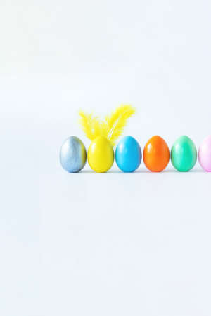 Top view of an easter composition of painted eggs in bright juicy colors on a white background with feather rabbit ears. Vacation concept, flat design, minimalismの写真素材