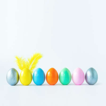 Top view of an easter composition of painted eggs in bright juicy colors on a white background with feather rabbit ears. Vacation concept, flat design, minimalismの写真素材
